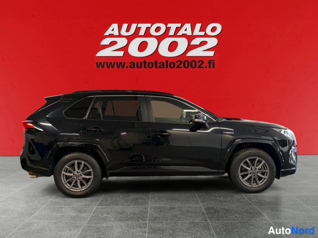 Takaviisto: Mustan Toyota RAV4:n sivuprofiili, korin kylki ja pyörät hallin harmaalla lattialla.