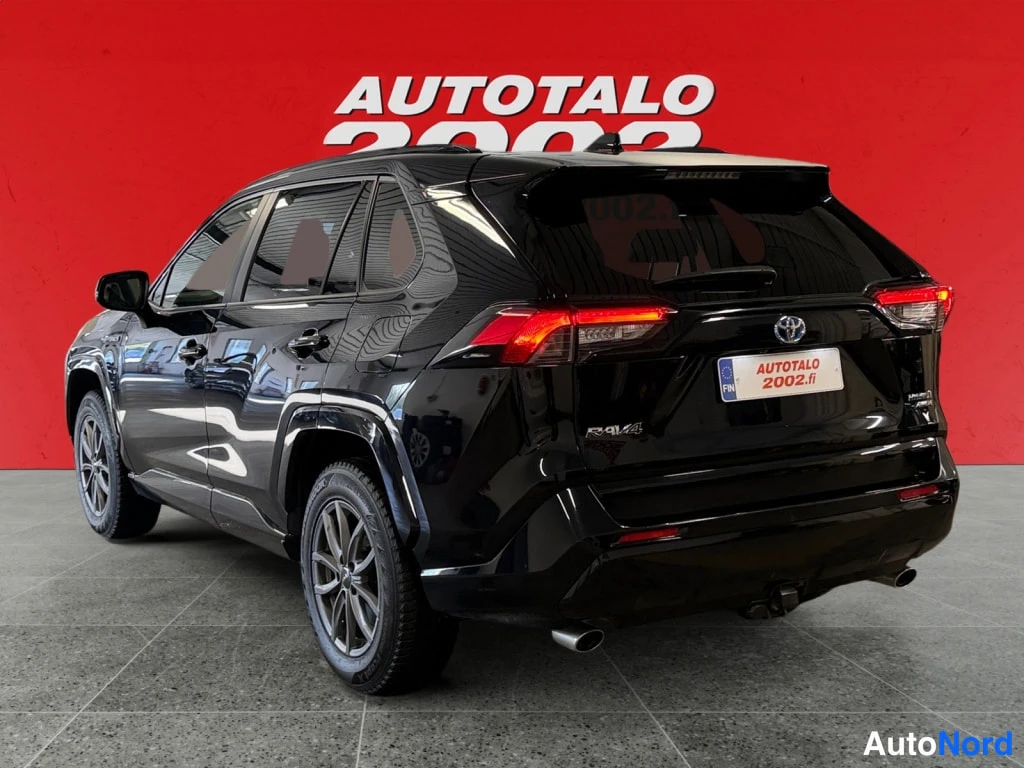 Takaviisto: Mustan Toyota RAV4:n takaosa ja vasen kylki kolmeneljänneskulmasta, punainen tausta.