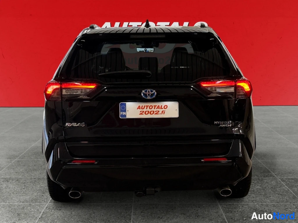 Takaa: Mustan Toyota RAV4:n suora takanäkyvys, takavalot ja C-hatck-taustaluukku, punainen tausta.