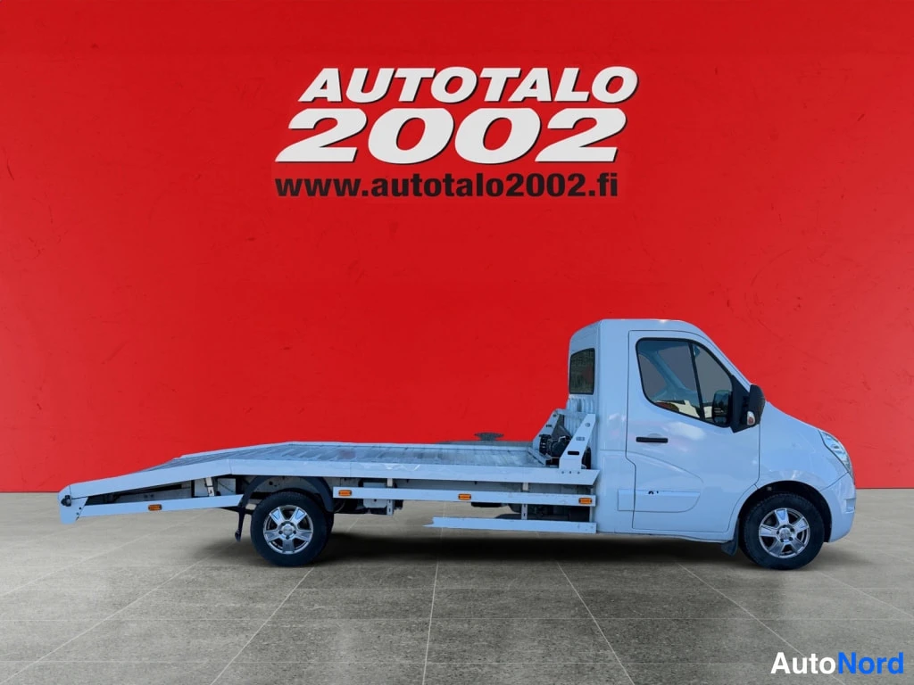 Sivulta: Valkoisen Renault Master -autonkuljetuslavetin sivunäkymä koko auton pituudelta, punainen taustaseinä ja Autoatalo 2002 -logo.