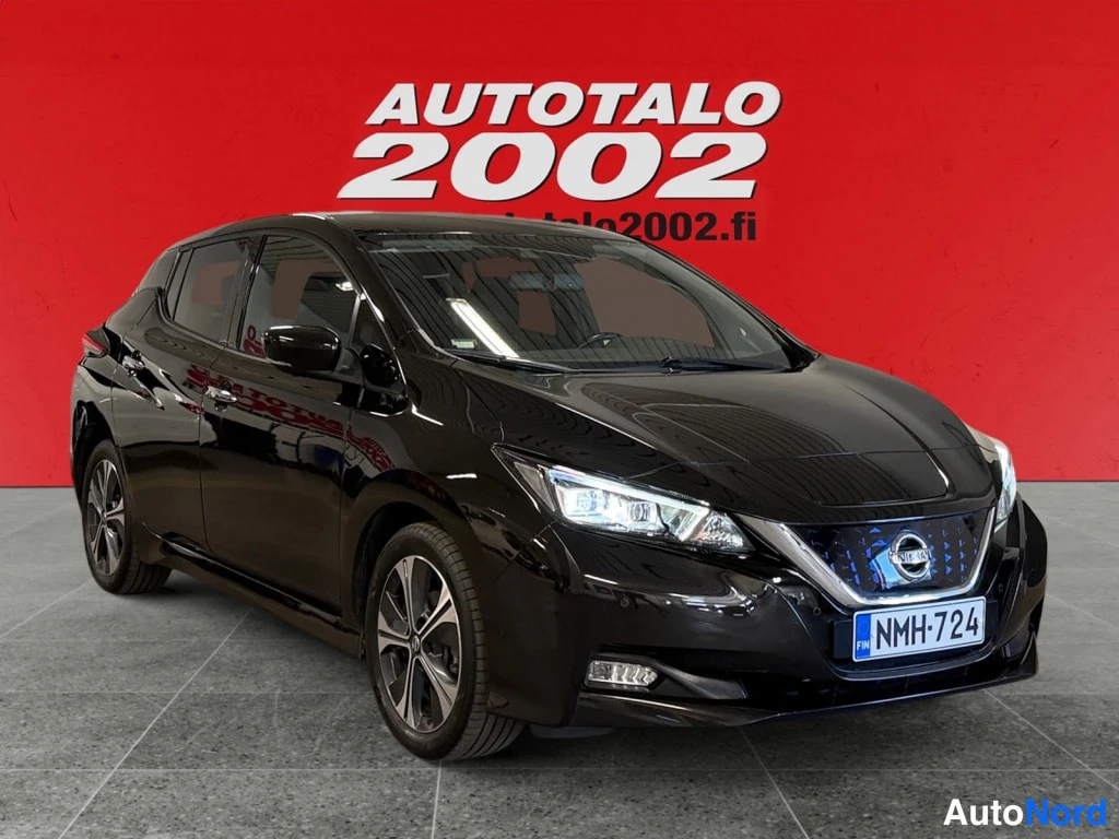 Etuviisto, nokka oikealle: Mustan Nissan Leaf -henkilöauton etukulma, etusäleikön Nissan-merkki ja rekisterikilpi näkyvissä punaisella taustalla.