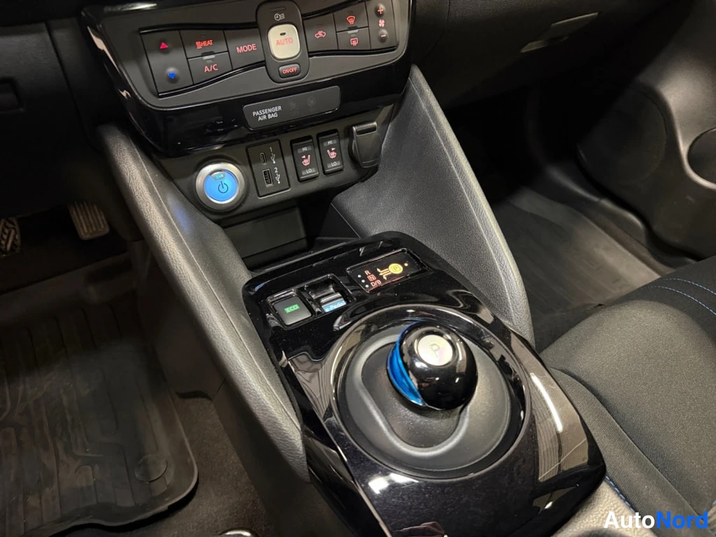 Muu: Keskconsole lähikuva: ilmastoinnin hallintaanappia, USB-portit, 12 V virtapistoke, seat heat/ventilation painikkeet, e-pedal-valinta ja automaattinen vaihteenva