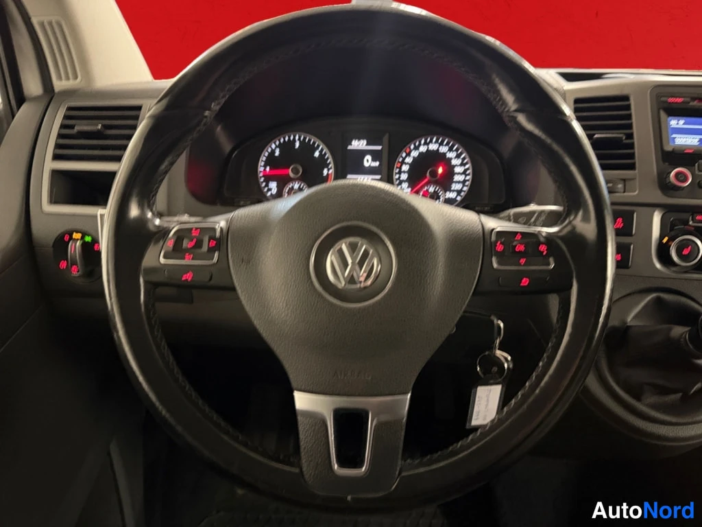 Edestä: Ohjaamo kuvattu kuljettajan paikalta: Volkswagen-merkitty ohjauspyörä, mittaristo, virta-avain ja radio.