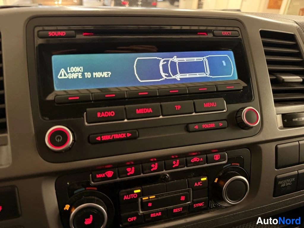 Edestä: Volkswagenin radio-näyttö (RCD 510) varoittaa tekstillä LOOK! SAFE TO MOVE? pysäköintitutkan karttakuvalla.
