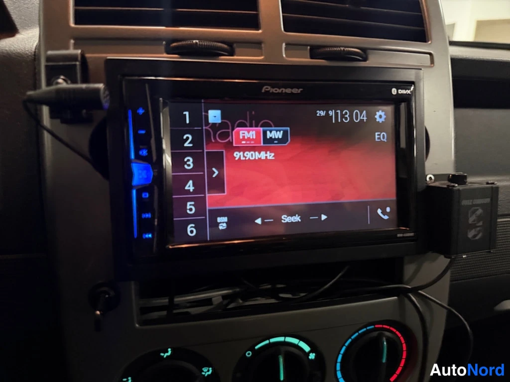 Muu: Pioneer-näytöllinen autoradio kojelaudassa, FM1 91,90 MHz, numeronäppäimet ja alla ilmastoinnin säätönupit.