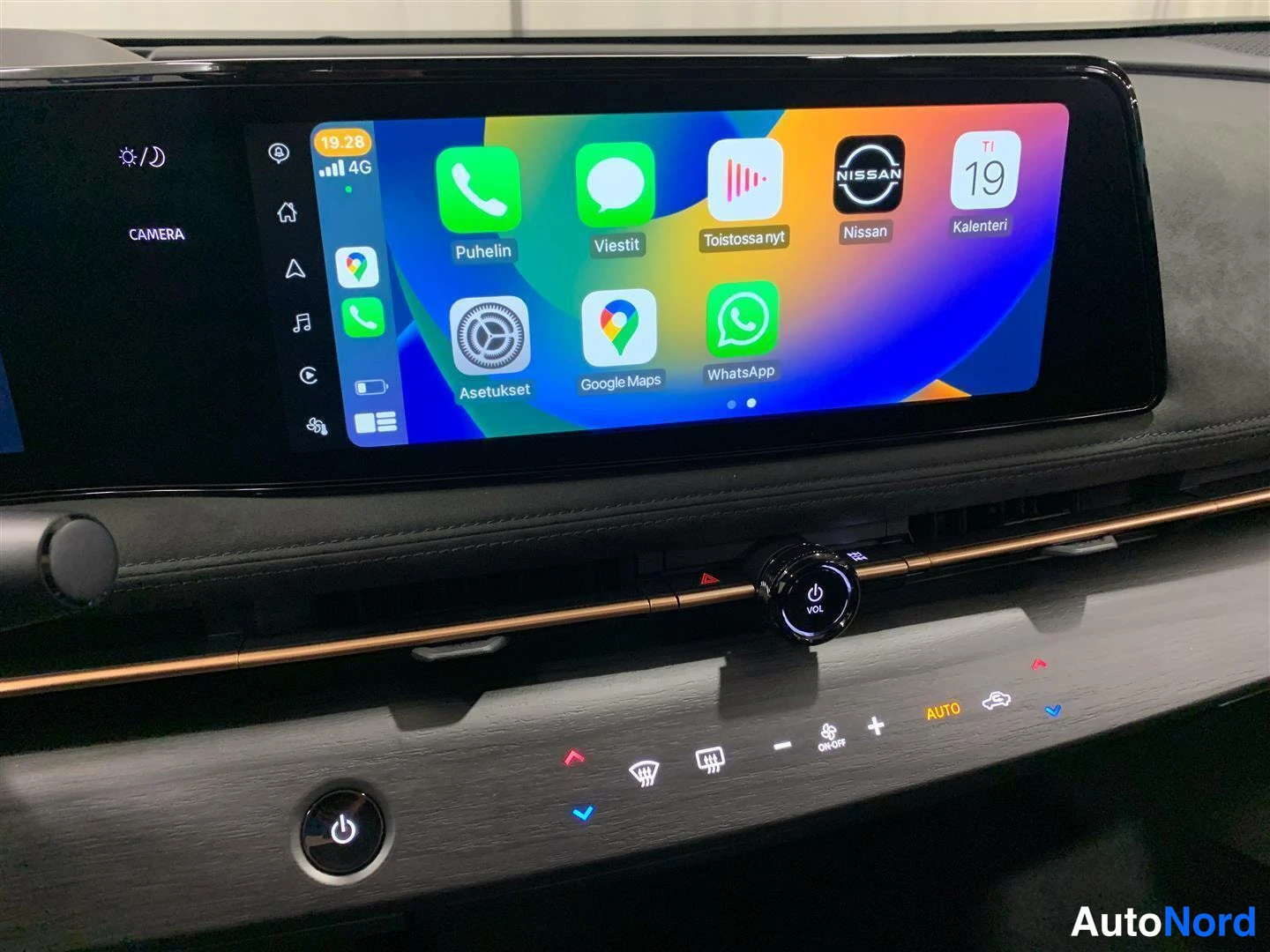 Muu: Kojetaulun näyttö näyttää Applen CarPlay-alkuruutua sovelluskuvakkeineen, alla äänenvoimakkuudensäädin ja ilmastointipainikkeet.