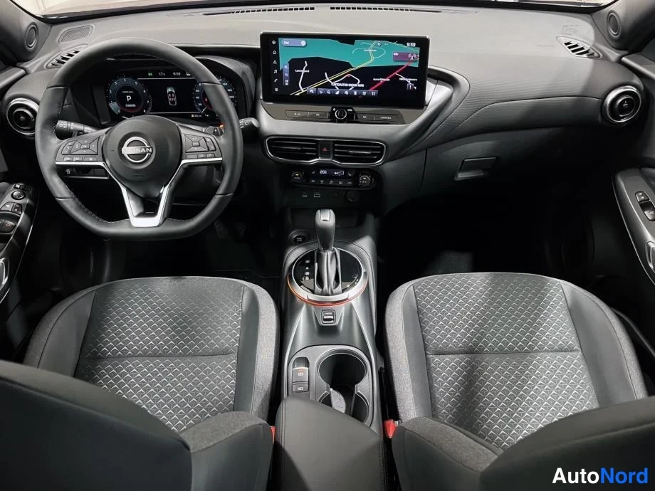Sivulta: Nissan Juke:n kojelauta ylhäältä kuvattuna: Nissan-merkkinen ohjauspyörä, digitaalinen mittaristo, keskusnäytöllä navigaatiokartta ja automaattivaihteen valitsi