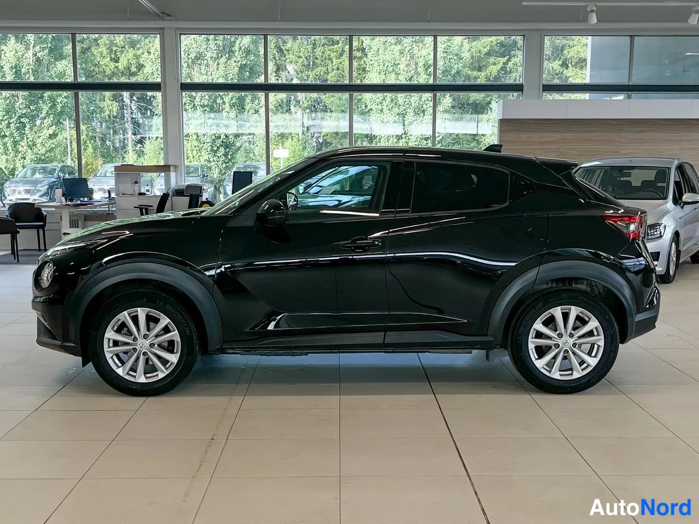 Sivulta: Mustan Nissan Juke -henkilöauton sivuprofiili oikealta puolelta showroomissa.