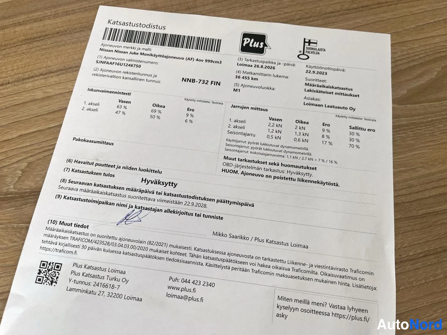 Muu: Katsastustodistus paperilla puupöydällä; rekisteritunnus, seuraava määräaikaiskatsastus 26.8.2026.