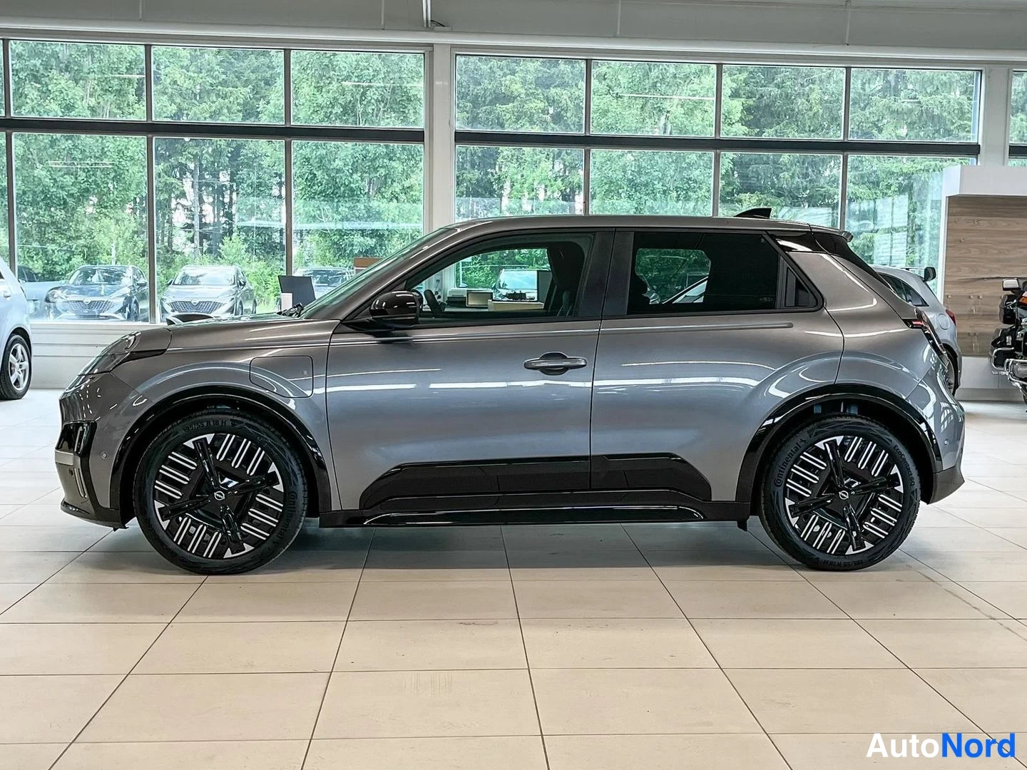 Sivulta: Nissan Micra -henkilöauto harmaana sivukulmasta vasen kylki showroomissa.