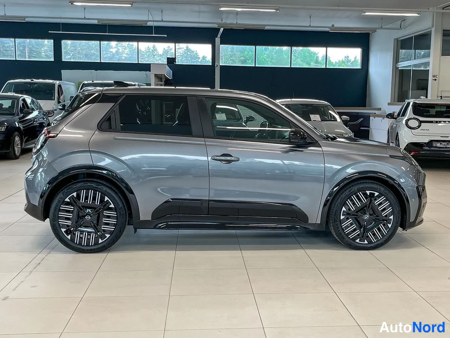 Sivulta: Nissan Micra -henkilöauto harmaana sivukulmasta oikea kylki autosalissa.