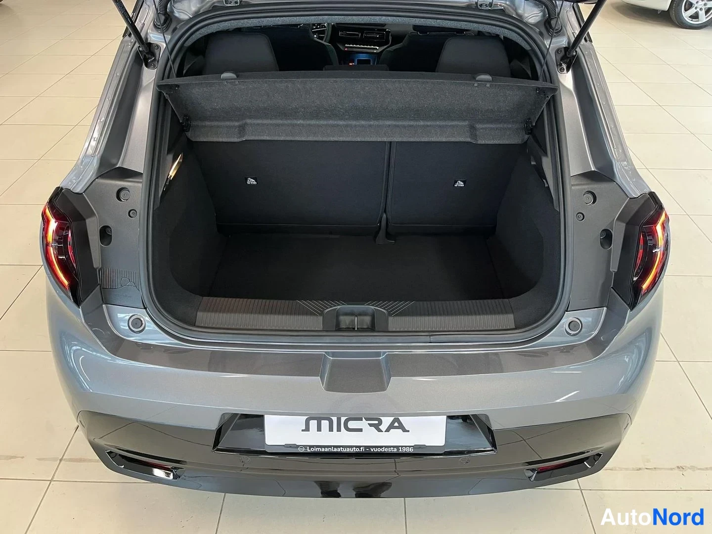 Takaa: Nissan Micran tavaratila avattuna ylhäältä kuvattuna; tumma matto ja irrotettava tukeva kuormaverho.