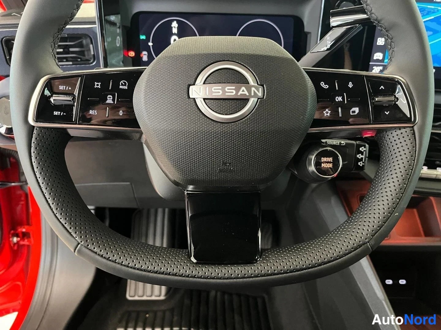 Muu: Ohjauspyörän lähikuva: NISSAN-logo keskellä, Drive Mode -valitsin ja monitoiminapit.