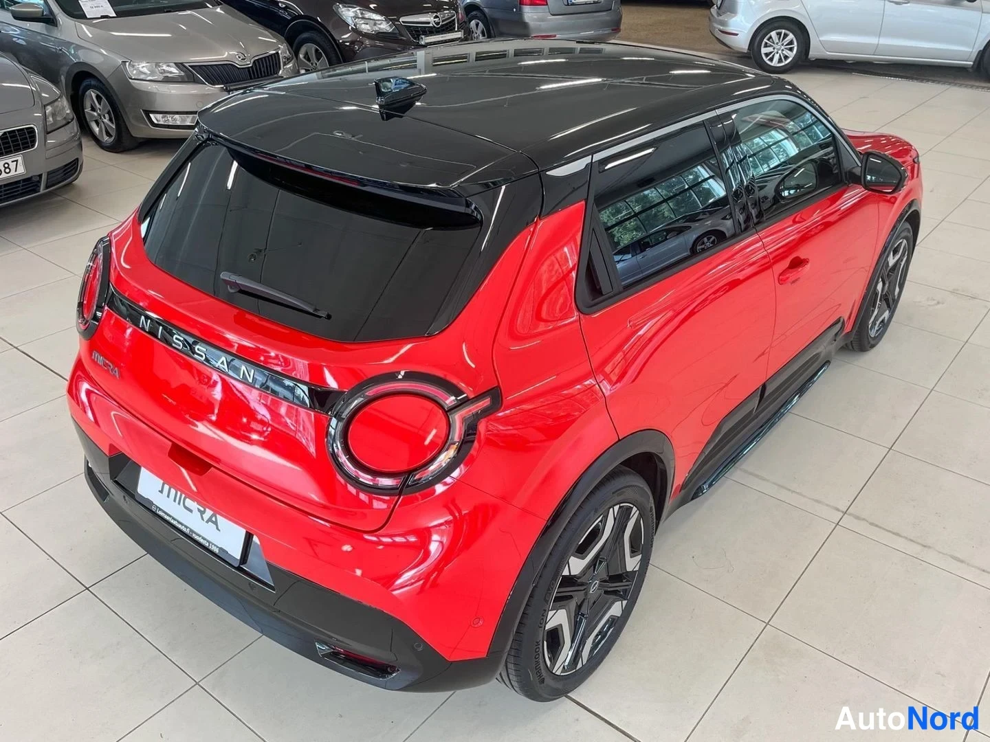 Takaviisto: Punainen Nissan Micra takanurkkakuva ylhäältä oikealta, musta katto, NISSAN-teksti takaluukussa.