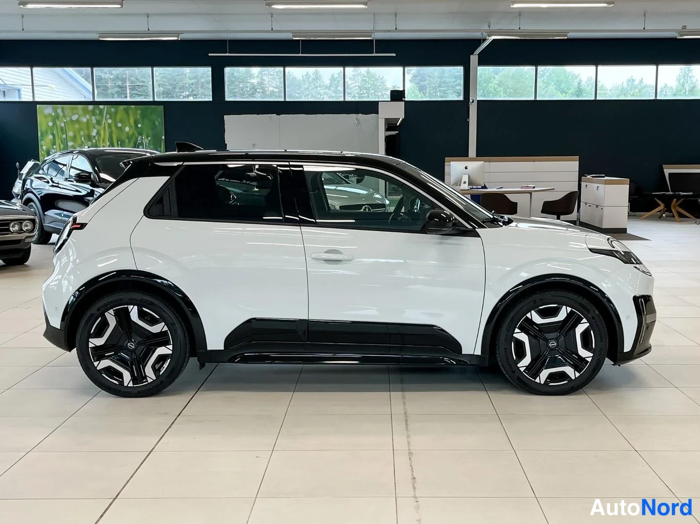 Sivulta: Valkoisen mustakattoisen Nissan Micran oikea kylki sivusuunnasta autonäyttelyssä.