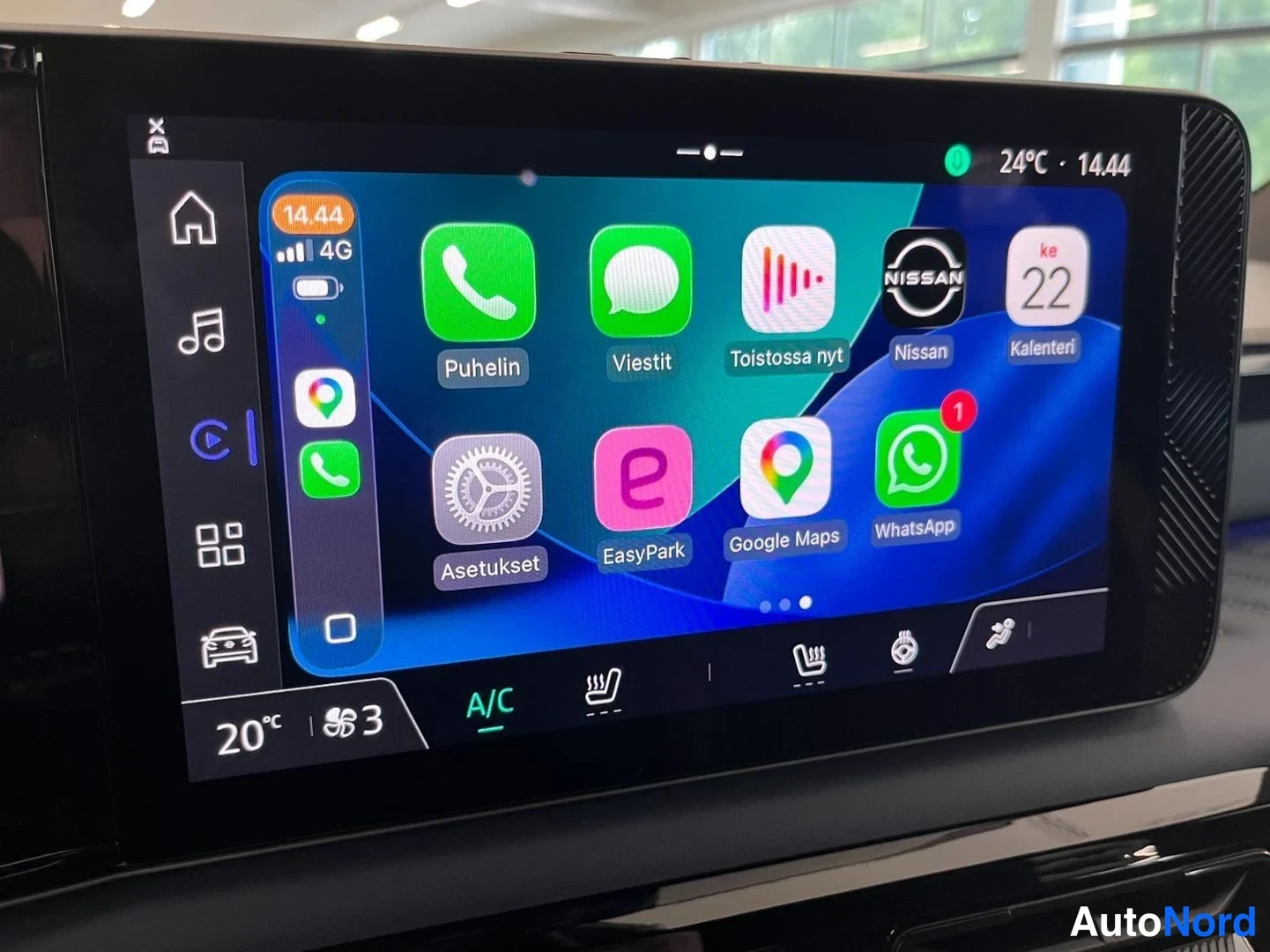 Yksityiskohta: Auton keskinäytön Apple CarPlay-näkymä sovelluksilla Puhelin, Viestit, Nissan, Kalenteri, Asetukset, EasyPark, Google Maps ja WhatsApp; ilmastointi A/C päällä.