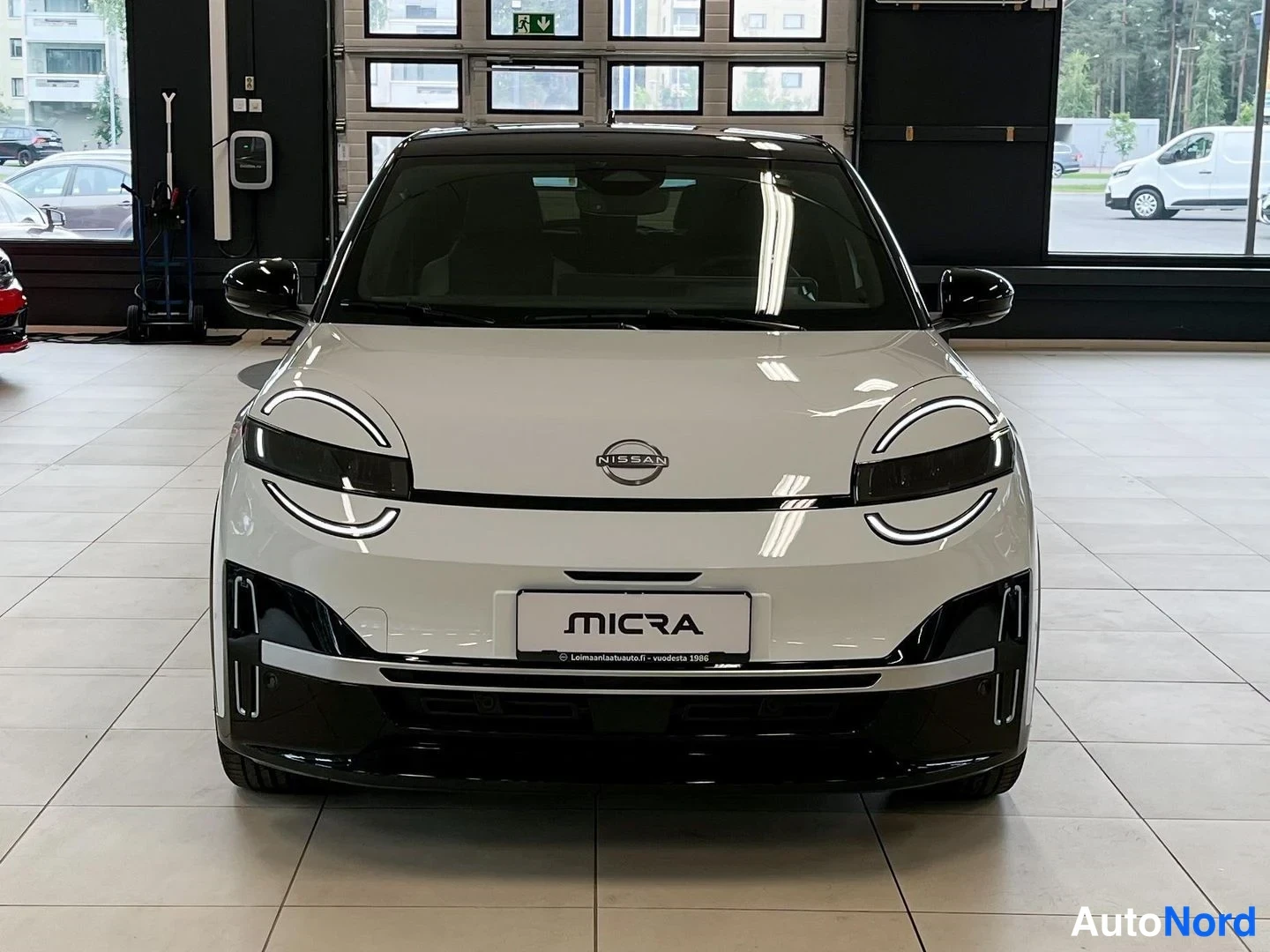 Edestä: Nissan Micran etupää edestäpäin; valkoinen korimalli, NISSAN-merkki keulalla ja MICRA-kyltti etupuskurin rekisteripaikalla.