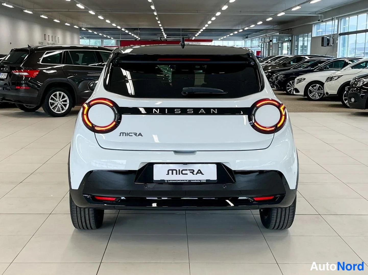 Takaa: Nissan Micran takapää suoraan takaa; pyöreät takavalot, NISSAN-teksti ja MICRA-merkintä takanapissa.