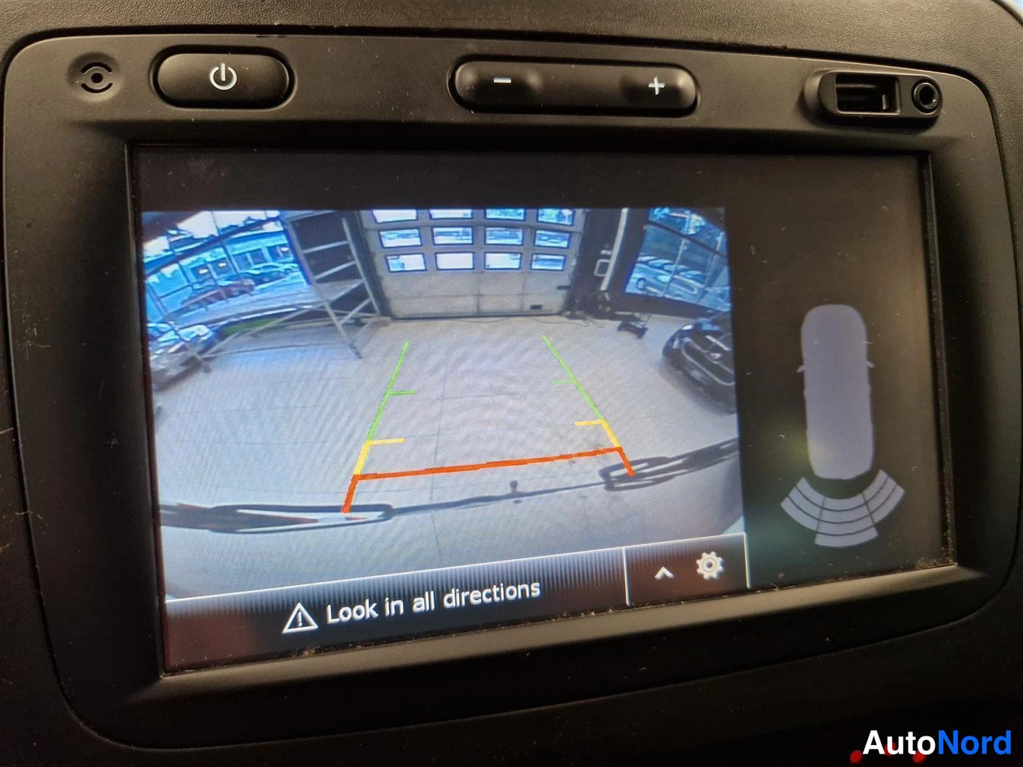 Muu: Auton infotainment-näytön kamera­näkymä, jossa on peruutushälytykset ja teksti 'Look in all directions'.