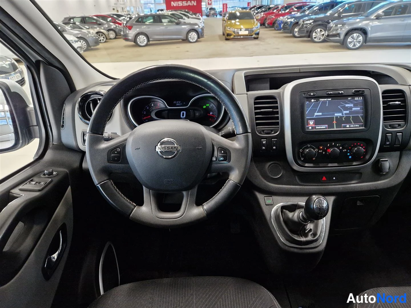 Edestä: Ohjaamosta: Nissan-ohjauspyörä, mittaristo ja navigointinäyttö, manuaalivaihtoleversi
