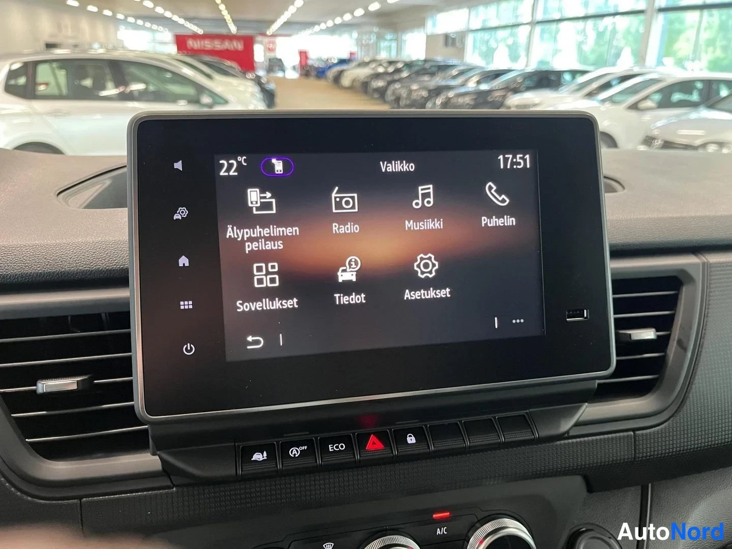 Yksityiskohta: Nissan Primastar -määrustuksen keskikonsolin kosketusnäyttö näyttää valikkoa radio-, musiikki- ja puhelinsovelluksineen; näytön alapuolella ECO- ja varoitusnapp