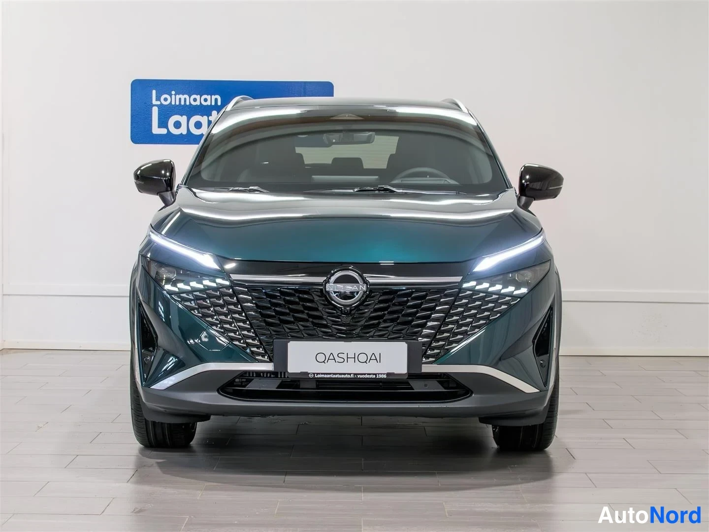 Edestä: Nissan Qashqai, etukuva osoittaa tummanvihreän korin, nokan, LED-ajovalot ja QASHQAI-kyltin etupuskurissa.