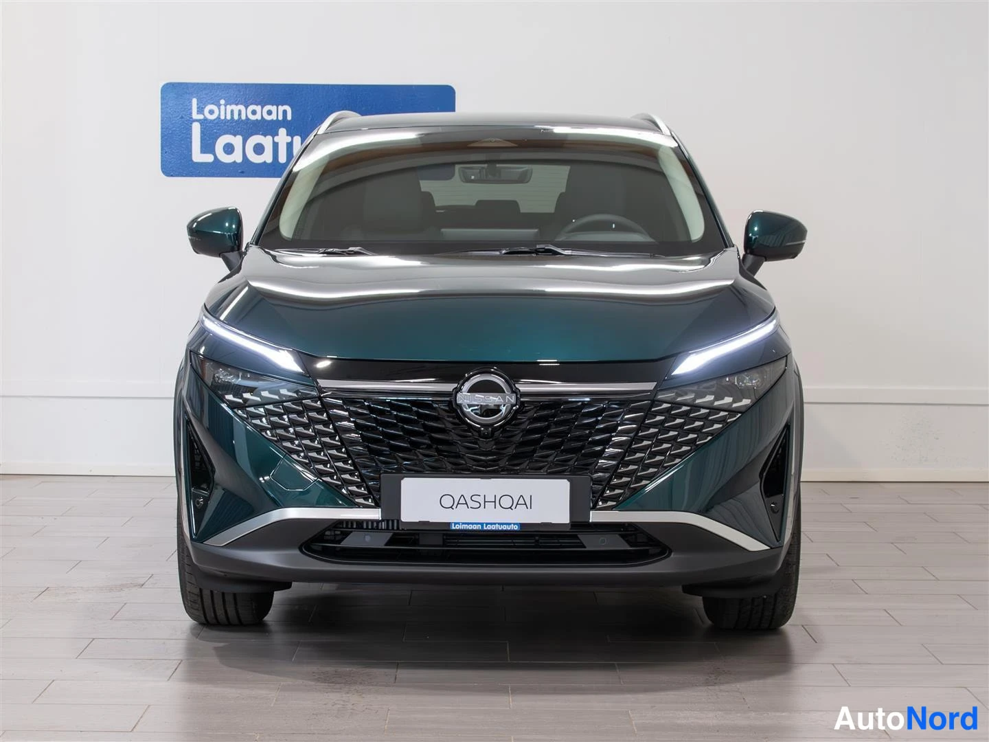 Edestä: Nissan Qashqai, tummanvihreä koriväri, edessäpäin kuvattuna sisätiloissa.