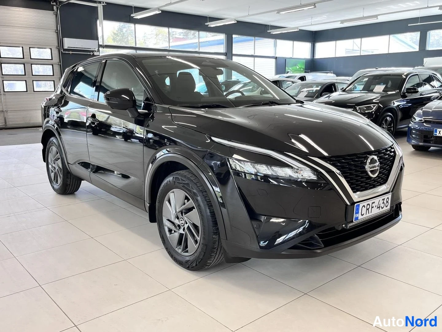 Etuviisto, nokka oikealle: Mustan Nissan Qashqain etunurkka kuvattuna vasemmalta, kohti koria kääntyvä etupanssari ja nokka oikealla, rekisterikilpi.