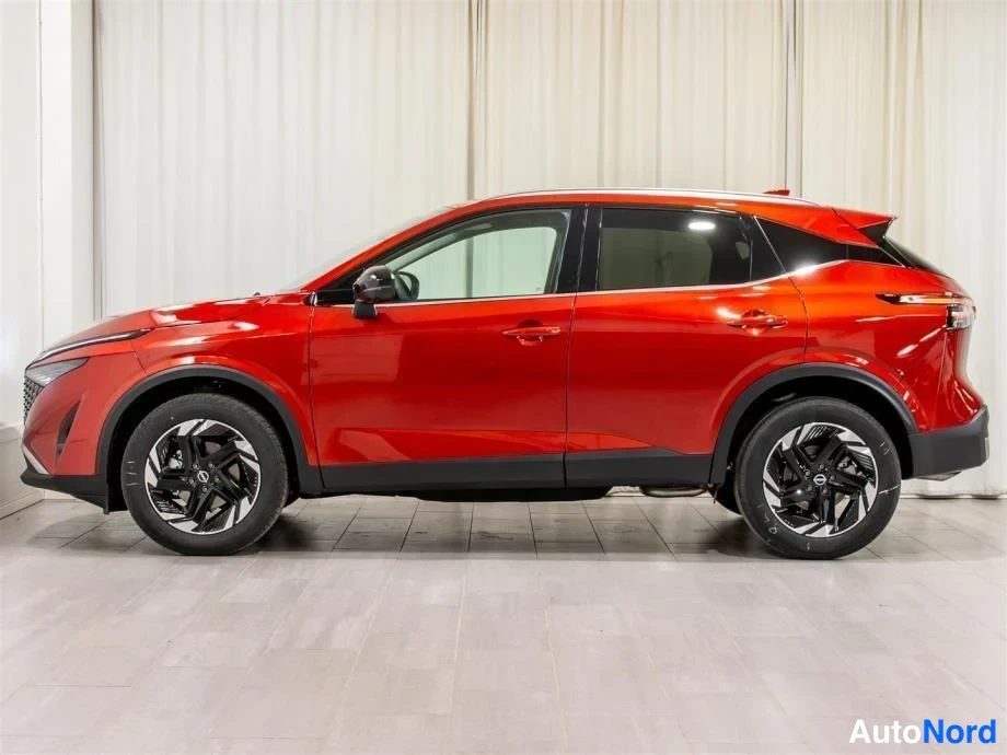 Etuviisto, nokka vasemmalle: Punainen Nissan Qashqai kyljestä vasemmalta, keula ja säleikön reuna näkyvät kuvan vasemmassa reunassa.