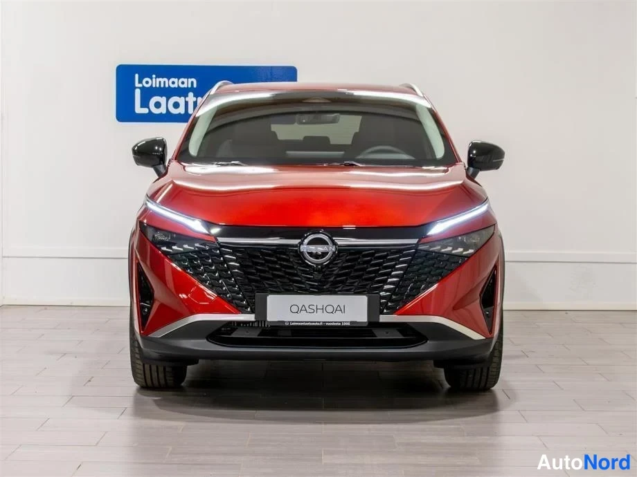 Edestä: Punaisen Nissan Qashqain etupään näkymä, suuri musta etusäleikkö ja ohut LED-päiväänajovalot