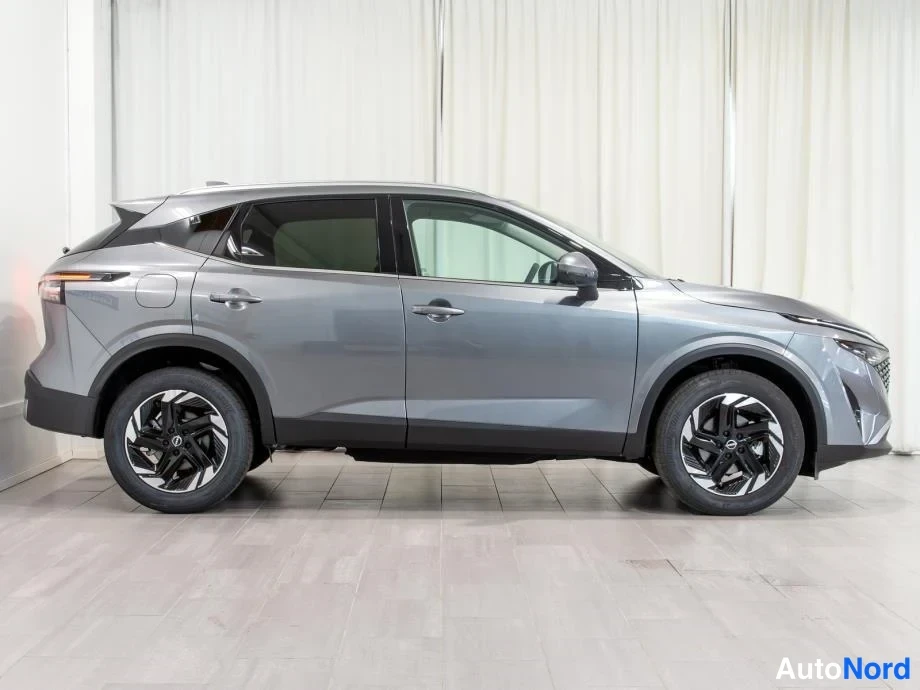 Sivulta: Nissan Qashqai -henkilöauto toiselta sivulta kuvattuna, keula osoittaa oikealle, harmaa koripaneelit ja ovien maalipinnasta luettuna.
