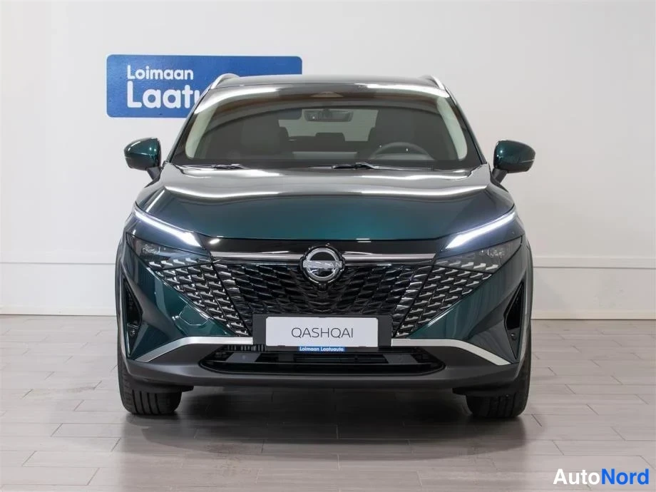 Edestä: Nissan Qashqai suoraan edestäpäin, tummanvihreä koripelti, verkkomainen etusäleikkö ja QASHQAI-kyltti.