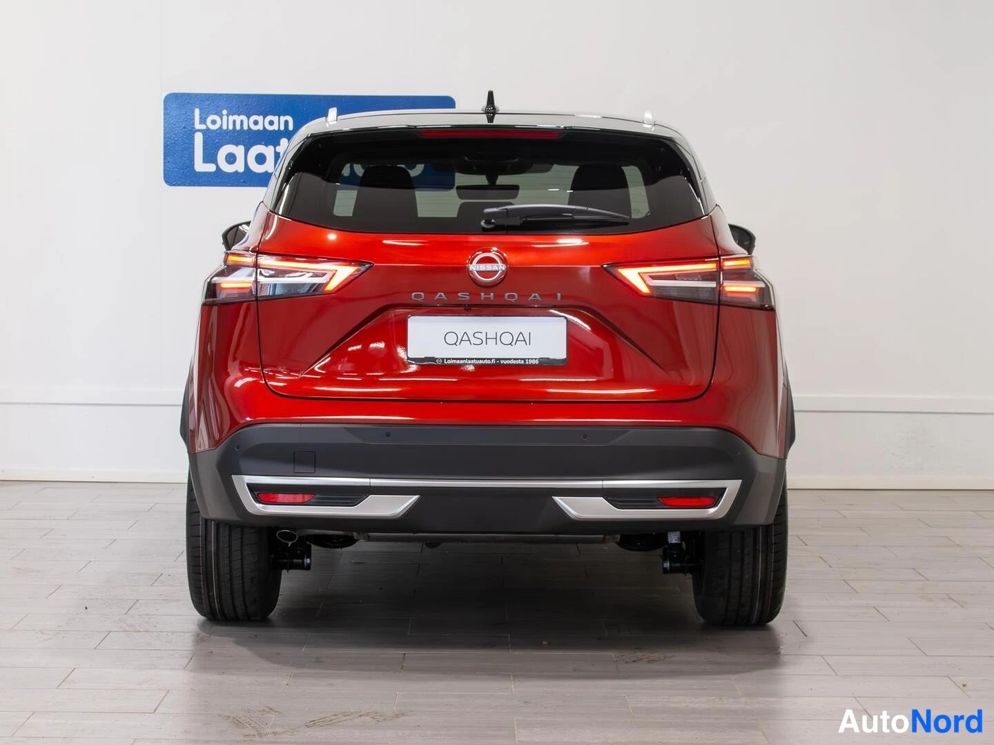 Takaa: Punaisen Nissan Qashqain takapää suoraan takaa; takavalot, QASHQAI-teksti ja perävaunun valo- ja heijastinkokonaisuudet.