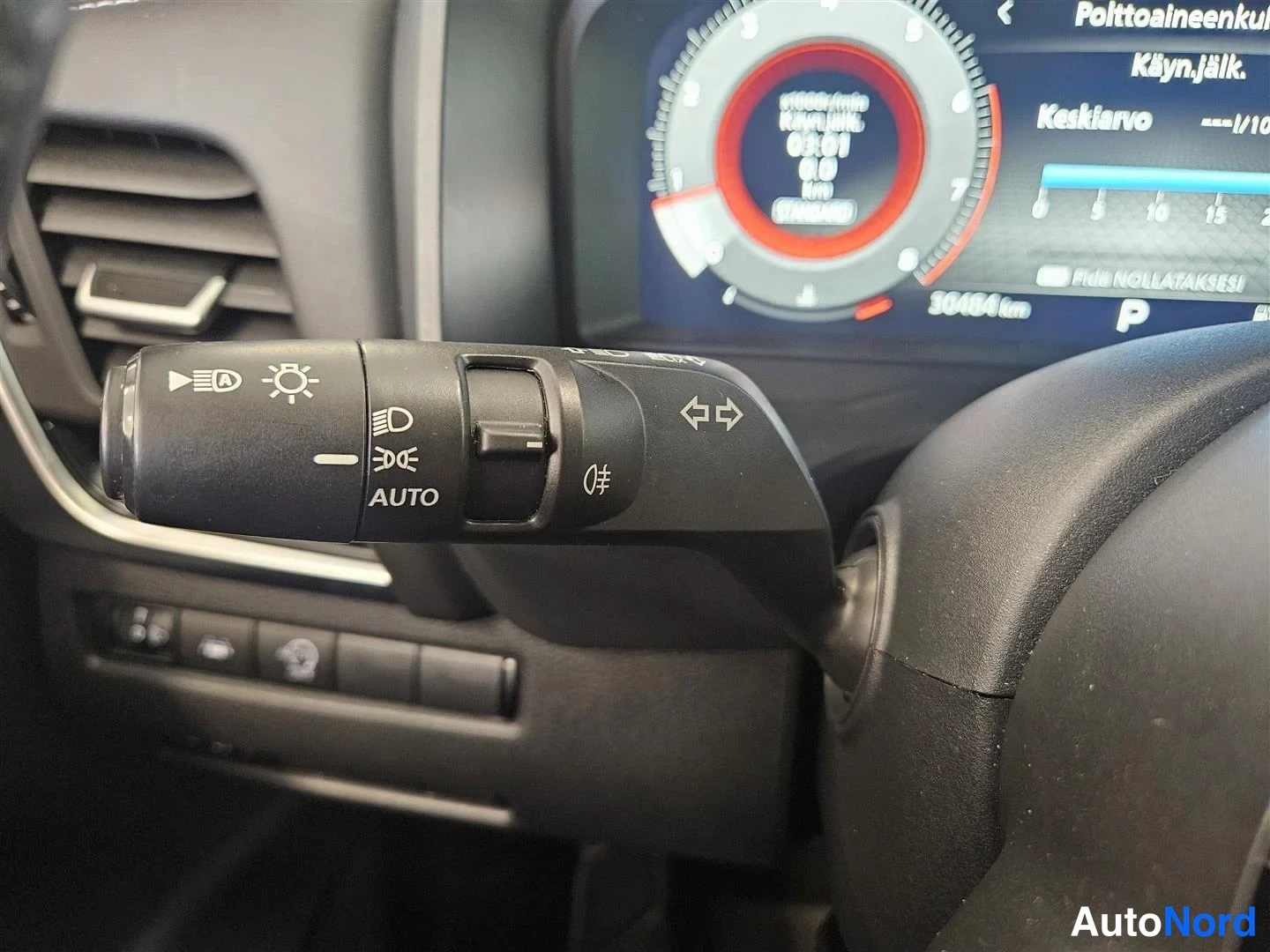 Muu: Sisätilakuva: ohjaustangon valokytkin, jonka sivulla AUTO-merkintä, sekä taustalla digitaalinen mittaristo, jossa näkyy 30484 km.