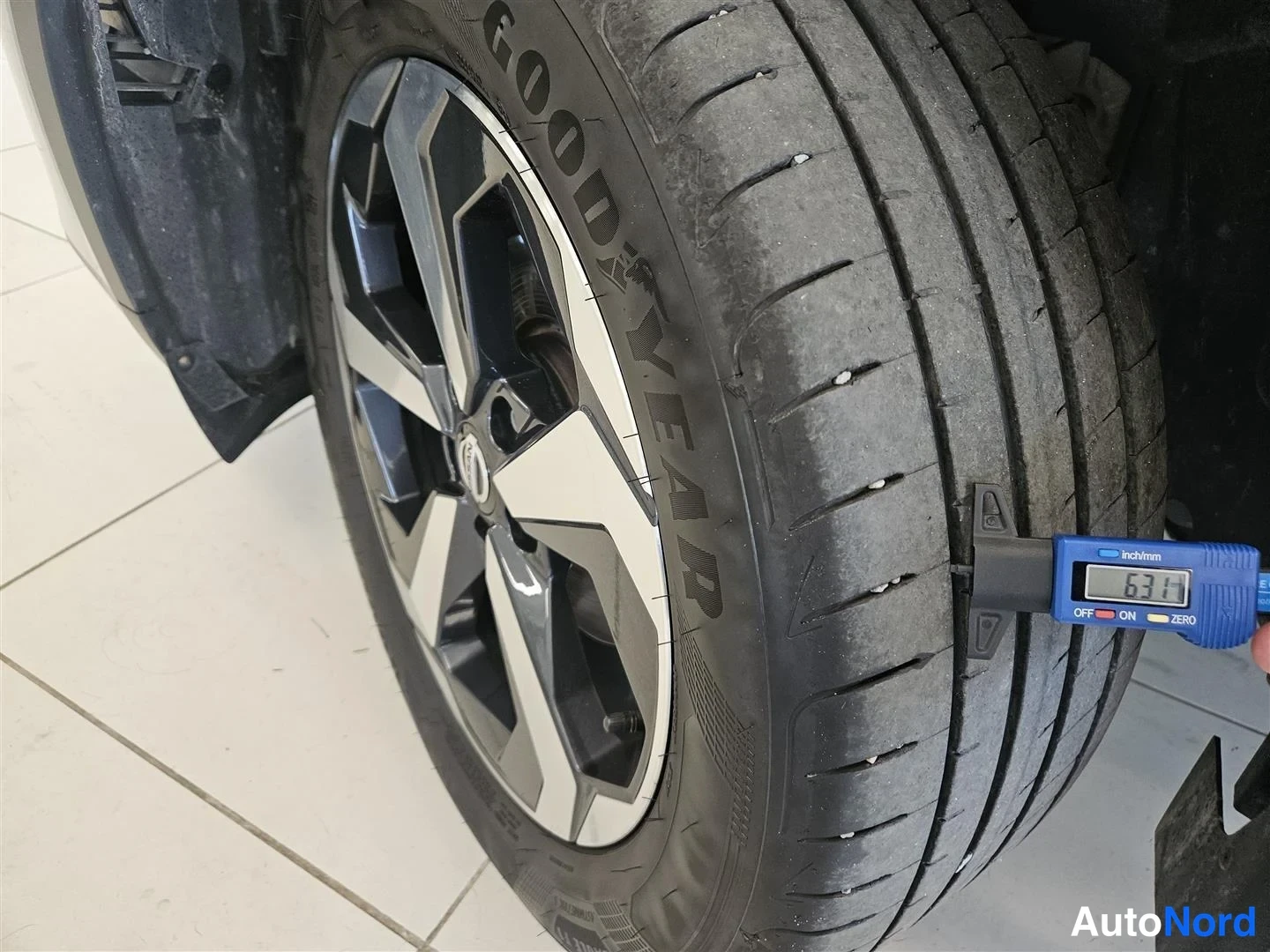 Yksityiskohta: Lähikuva auton takapyörästä Goodyear-kesärengkaassa; rengaspaine- ja uramittalaitteen näyttö lukee 6,34.