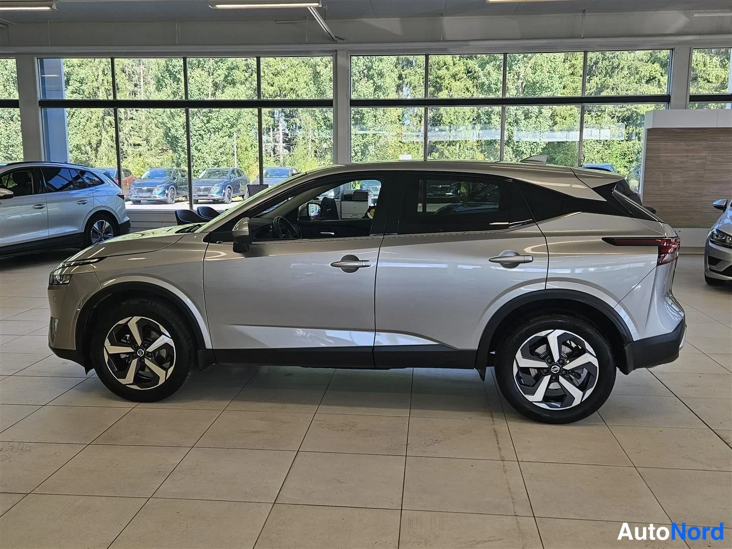 Sivulta: Nissan Qashqai sivulta kuvattuna auton vasemmasta kyljestä; kylkilinjat, ovet ja kevytmetallivanteet näkyvät.