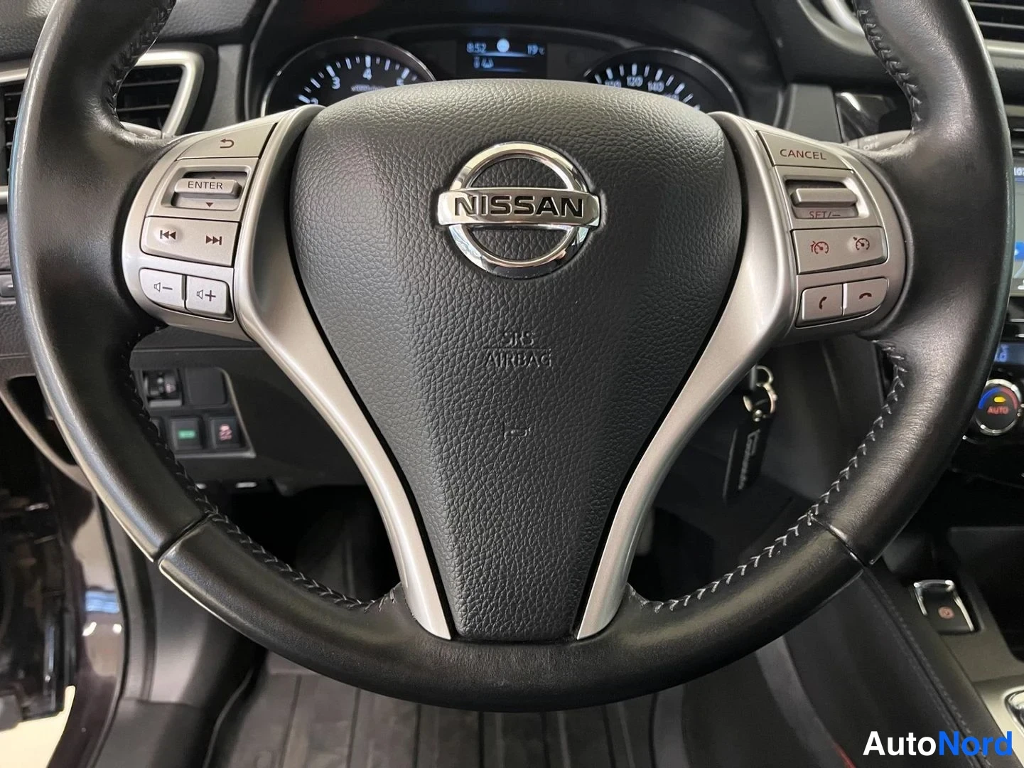 Muu: Ohjauspyörän keskusta lähikuvassa: Nissan-logo, SRS AIRBAG-merkintä ja monitoiminäppäimet, taustalla mittaristo.
