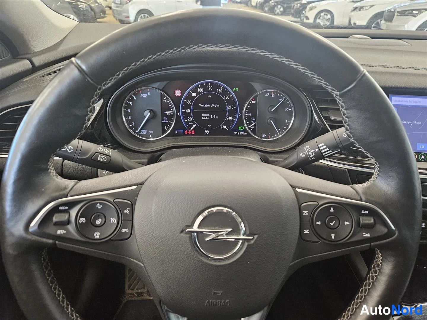 Muu: Opel-ohjauspyörä ja mittaristo: nopeusmittari, kierroslukumittari ja matkamittari 91 219 km, näytössä tieopastietoa.