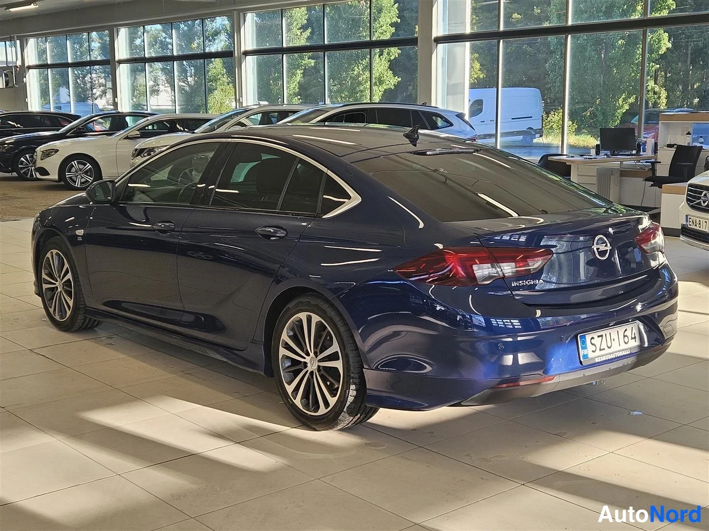 Takaviisto: Opel Insignia sivulta-takaa; rekisterikilpi, sininen kori, kevytmetallivanteet ja takavalot näkyvät autosalissa.