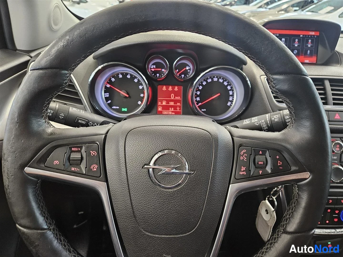 Yksityiskohta: Opel-ohjauspyörä ja mittaristo edestä: nopeusmittari, kierrosmittari ja polttoainemittari, keskellä punainen näyttö, jonka lukema on 138720 km. Ohjauspyörän nap