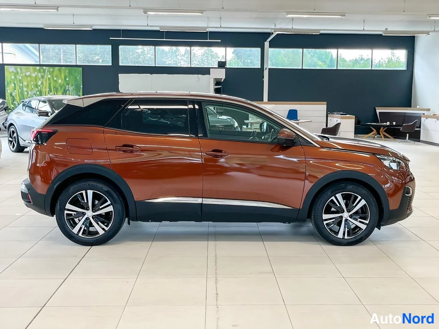 Takaviisto: Peugeot 3008:n takaosan sivuprofiili autohallissa, tummat C-pylväät ja hopeiset kevytmetallivanteet.