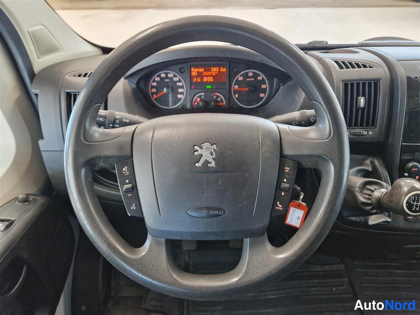 Muu: Lähikuva ratista: Peugeotin leijonatunnus ja Air bag -teksti, kojelaudan mittarit ja näyttö taustalla.