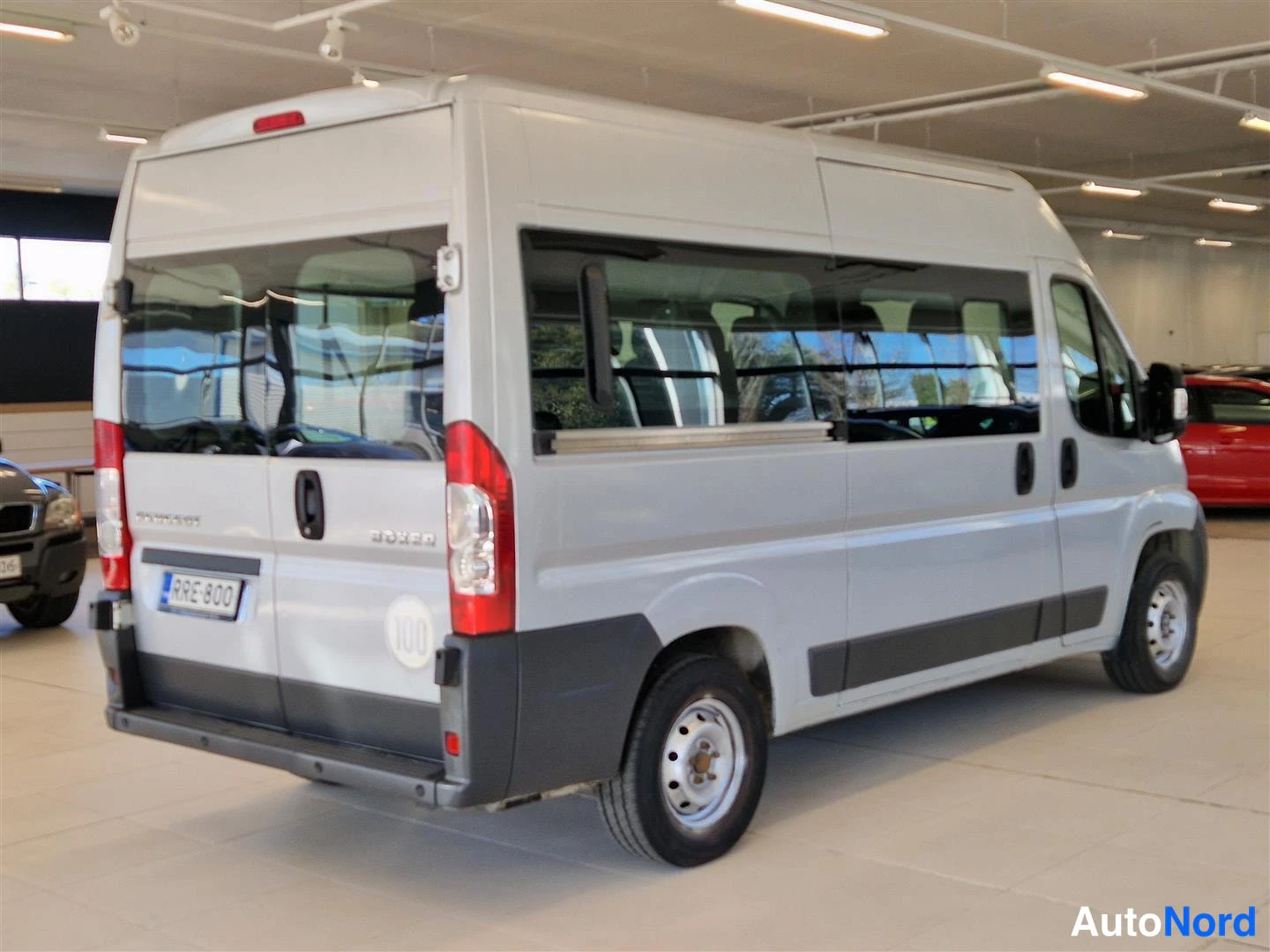 Takaviisto: Hopeanharmaa Peugeot Boxer -pakettibussi takanurkkakulmalta kuvattuna; takapariovet, BOXER-teksti ja rekisterikilpi näkyvät automohteerin sisätiloissa.