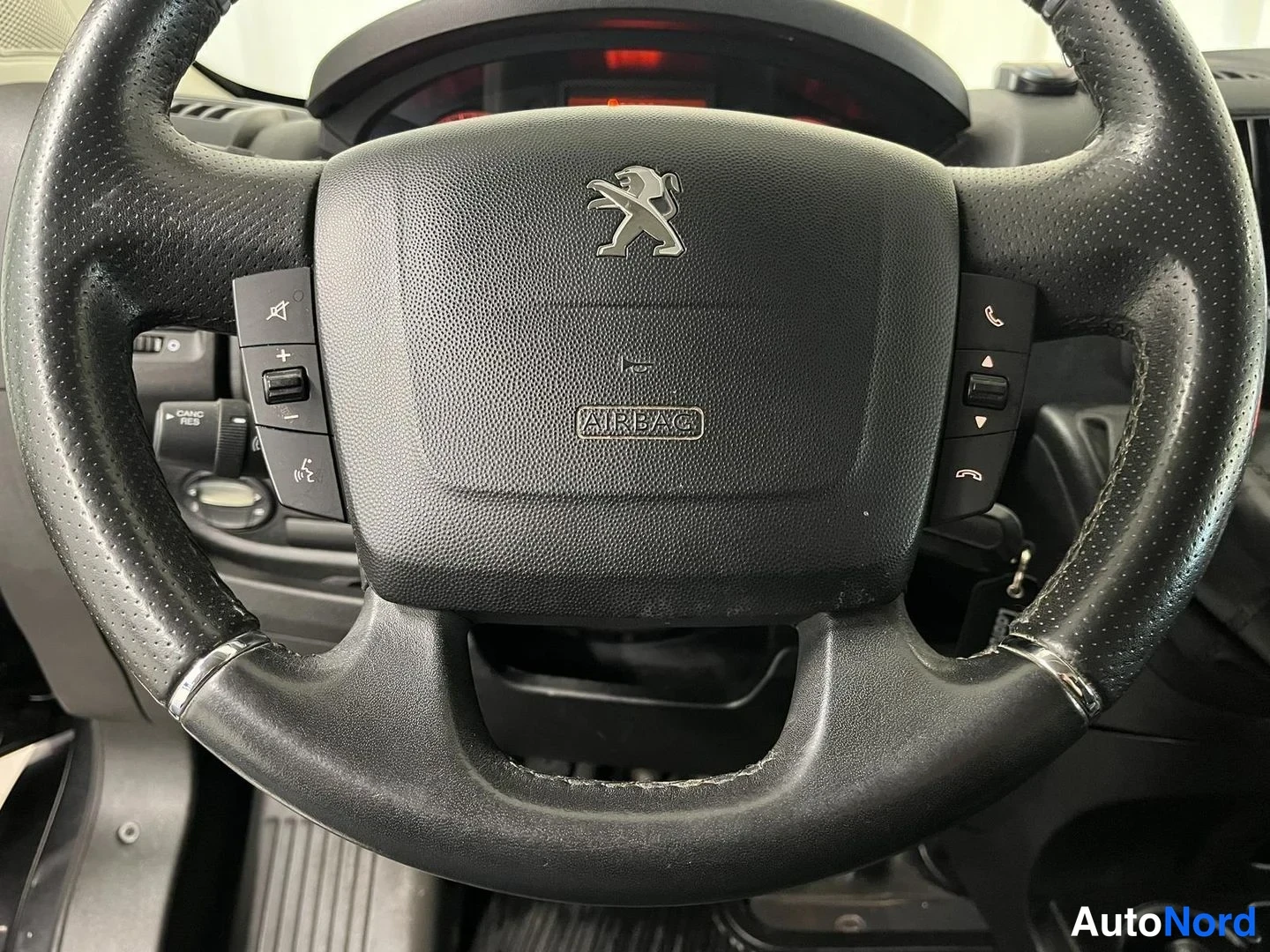 Yksityiskohta: Ohjauspyörän lähikuva: Peugeot-leijona, AIRBAG-teksti ja monitoiminäppäimet.