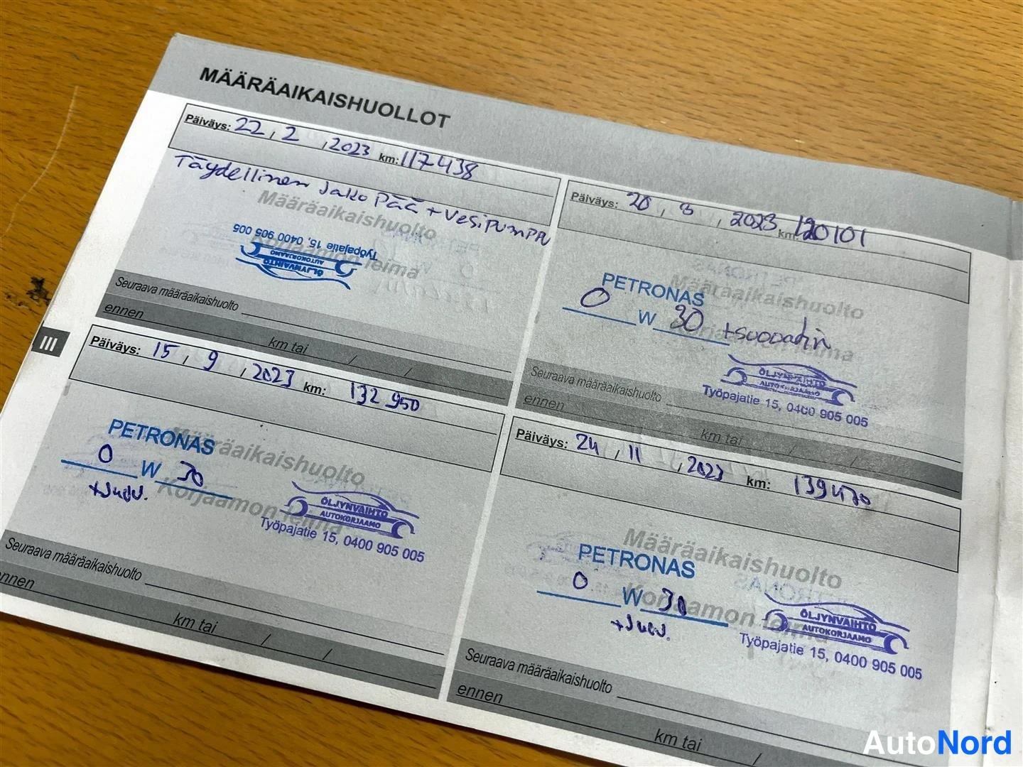 Yksityiskohta: Huoltokirjan sivu vuosien 2023 huoltoja merkitty, PETRONAS 0W-30 -öljymerkinnät