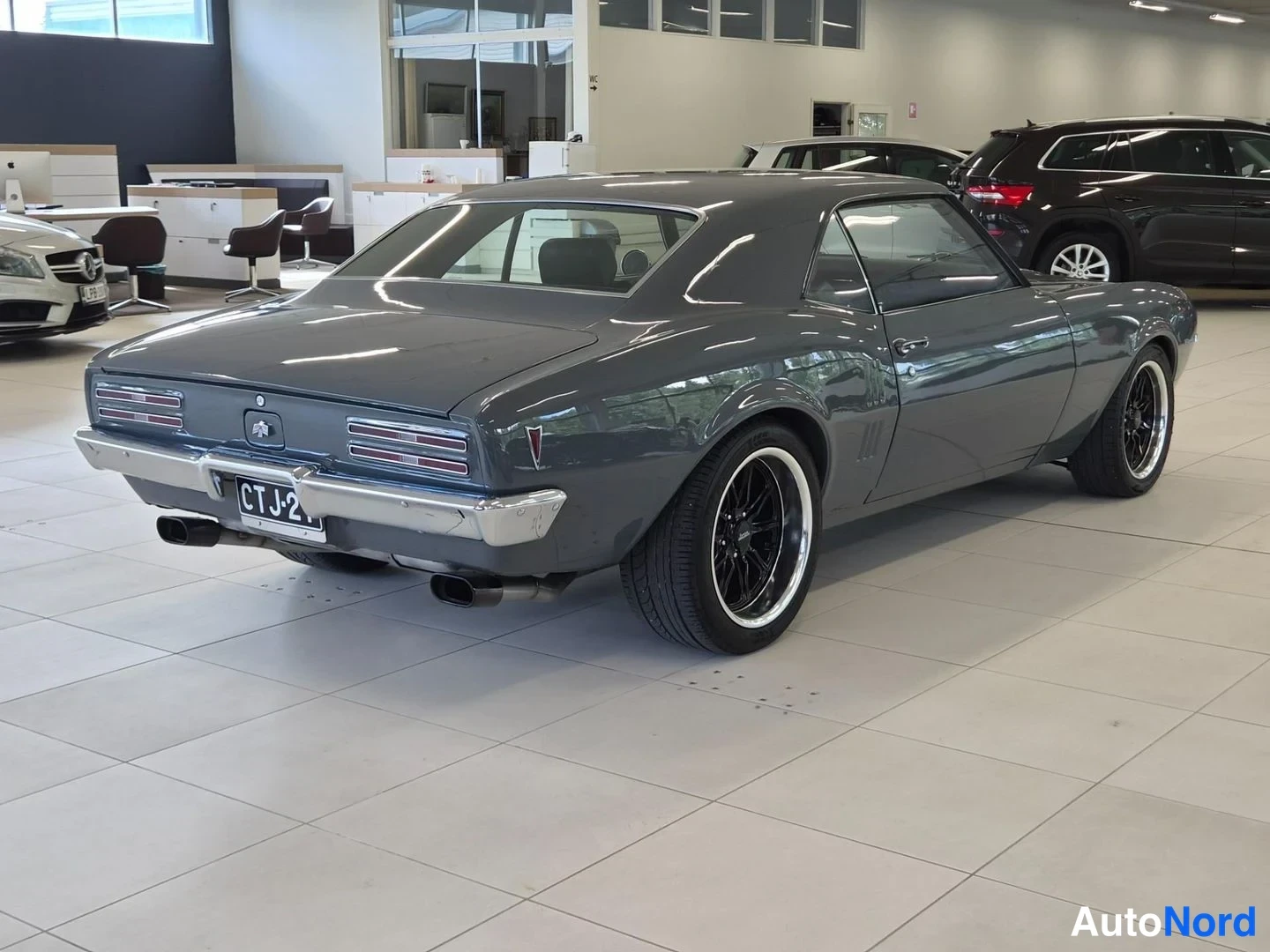Takaviisto: Harmaan Pontiac Firebird -auton takakolmasosa autonhallissa, rekisteritunnus ja pakanmustat vanteet näkyvät.