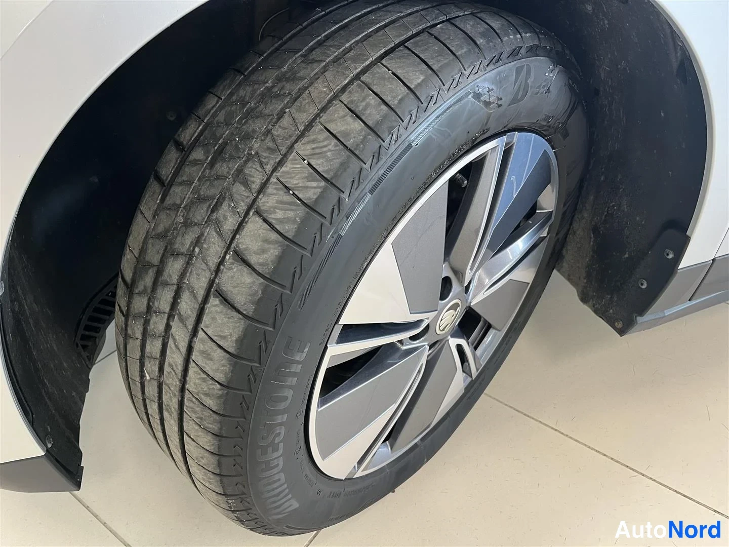 Yksityiskohta: Sivukulma: etupyörä ja runsaasti kulunut Bridgestone-tyynnyrilevy, hopeinen ja musta kevytmetallivanne; renkaan kylki ja kulutusjälki selviävät
