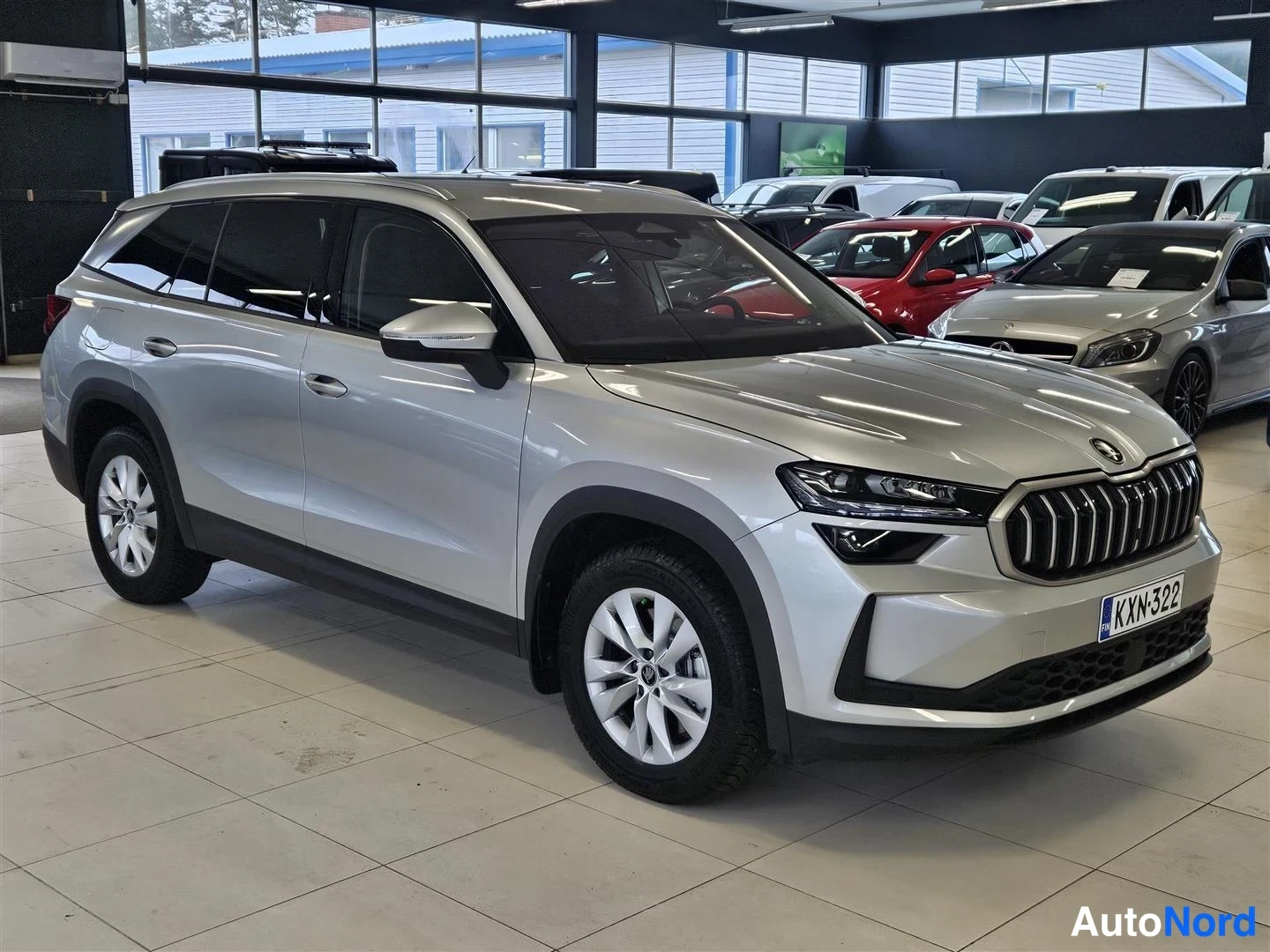 Etuviisto, nokka oikealle: Hopeanvärinen Škoda Kodiaq -maasturin etukulmanäkymä autohallissa, rekisterikilpi.