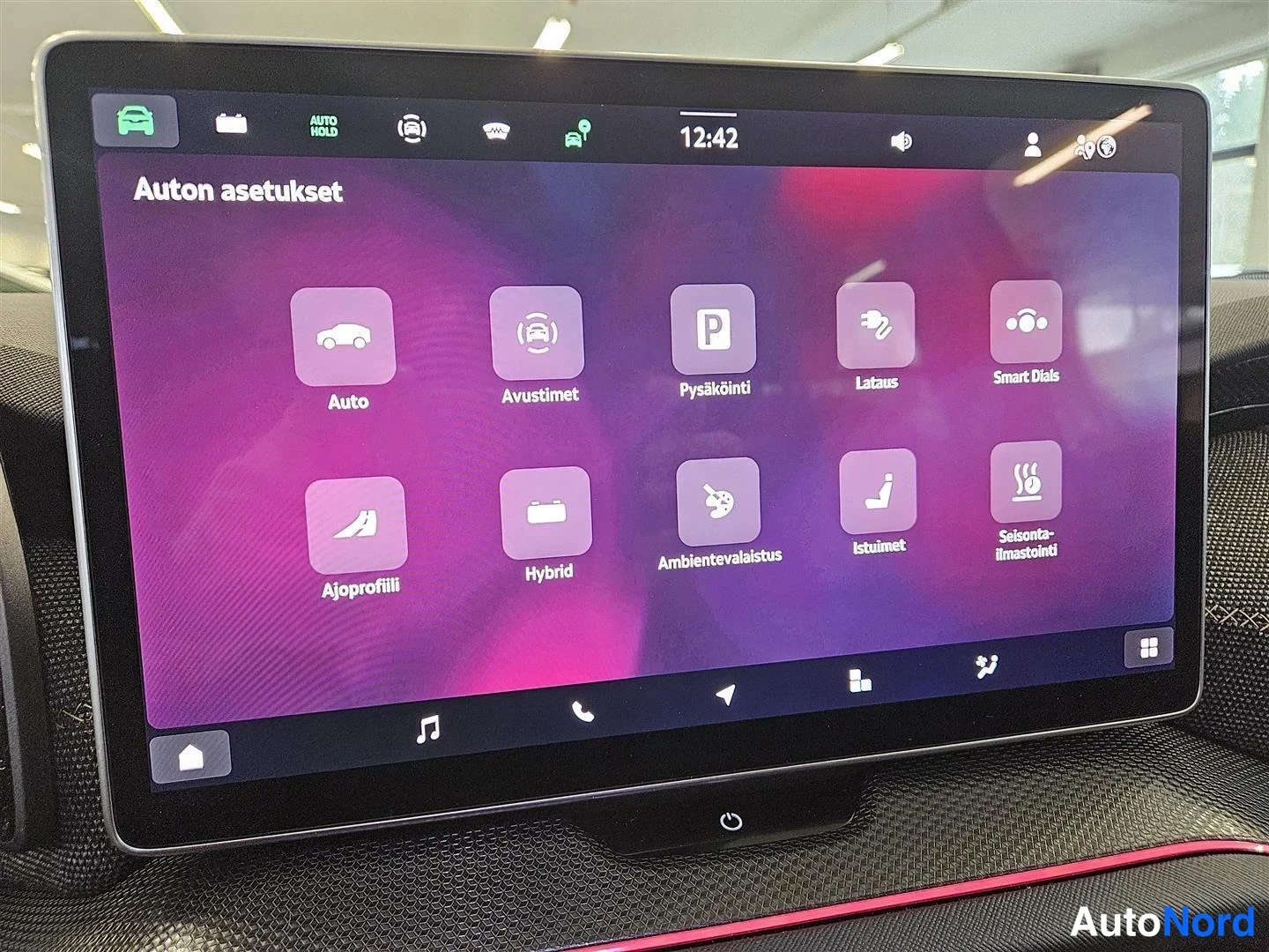Edestä: Auton infotainment-näyttö Auton asetukset -valikossa: kuvakkeet Auto, Avustimet, Pysäköinti, Lataus, Smart Dials, Ajoprofiili, Hybrid, Ambientevalaistus, Istuim