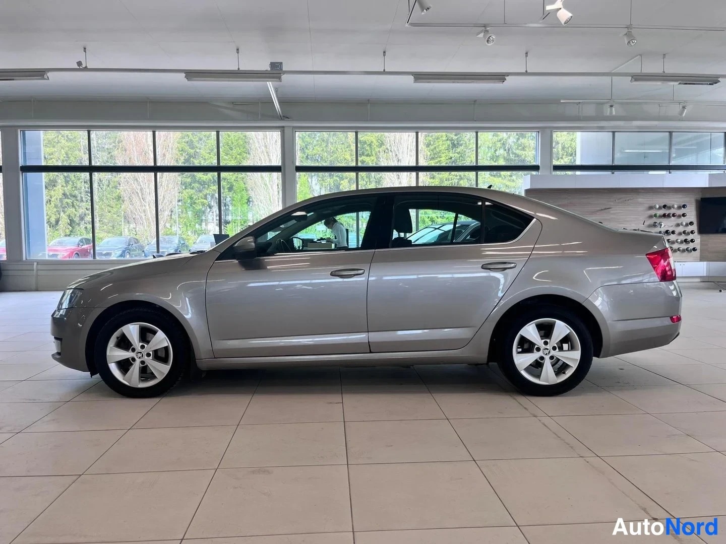 Sivulta: Beige Skoda Octavia -sedan sivuprofiili vasemmalta myymälässä.